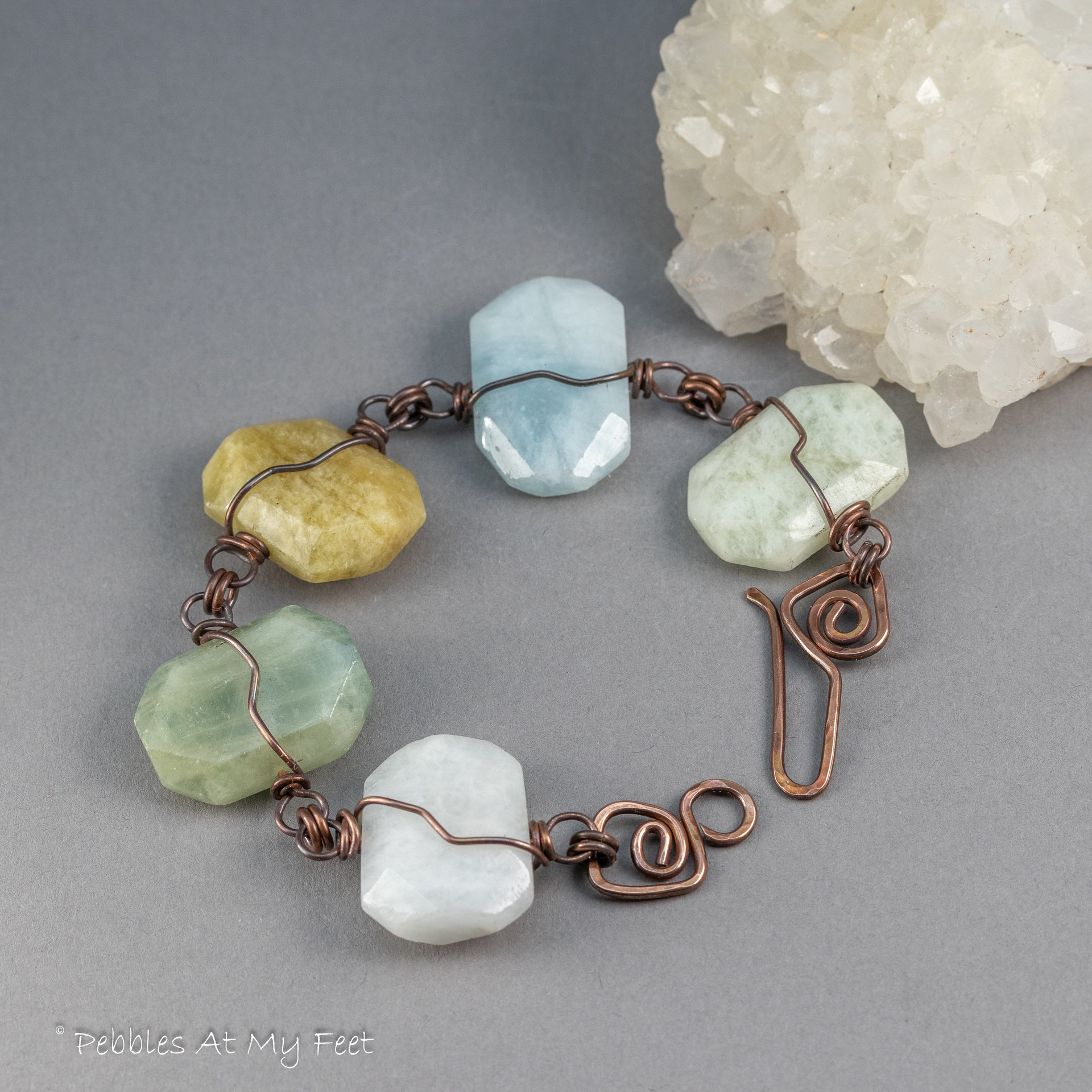 A Stone and Copper Bracelet with a Unique Handcrafted Hook Closure Displayed on a Gray Background